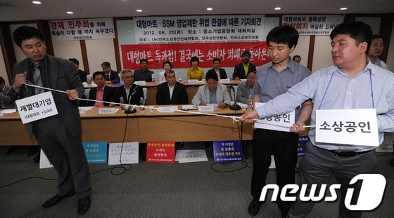 전국소상공인단체연합회 회원 및 관계자들이 지난 25일 서울 여의도 중소기업중앙회에서 열린 대형마트·SSM 영업제한 위법 판결에 따른 기자회견에서 대기업과 소상공인의 관계를 밧줄을 이용해 퍼포먼스를 벌이고 있다. 2012.6.25/뉴스1 © News1 양동욱 기자