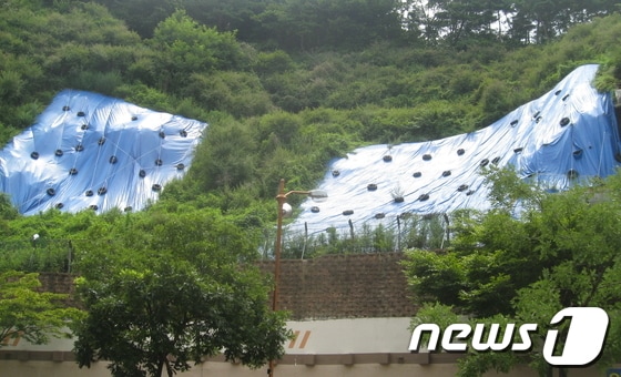 1999년 건립한 울산 울주군 청량면 쌍용하나빌리지아파트의 급경사지 일부의 지난해 8월께 모습. 아파트 측이 붕괴를 막기 위해 방수포를 덮고, 배수로를 정비하는 등의 조치를 취하고 있지만 예산 규모 등으로 인해 보강에 어려움을 겪고 있다. © News1 김규신 기자