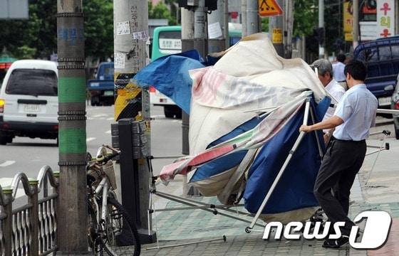 초강력 태풍 '볼라벤(BOLAVEN)' 영향으로 전국 곳곳에서 피해가 발생하고 있는 28일 오후 서울 동대문구 떡전사거리 인근 인도에서 상가 관계자들이 강풍에 날린 천막을 치우고 있다. © News1 허경 기자