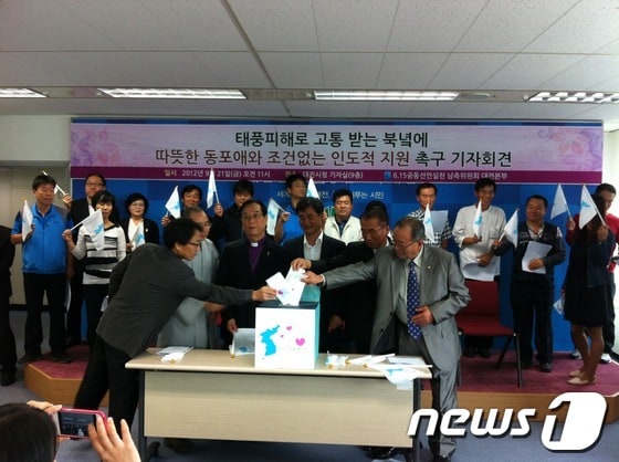 6·15공동선언실천 대전본부가 21일 대전시청 브리핑실에서 조건 없는 대북 수해복구 지원을 촉구하는 기자회견을 열고, 다음 달 중순까지 밀가루 30t(1500만 원 상당)을 목표로 수해지원 모금을 진행한다고 밝혔다. 대전본부 관계자들이 한반도가 표시된 모금함에 각자 모금액을 넣고 있다. © News1 