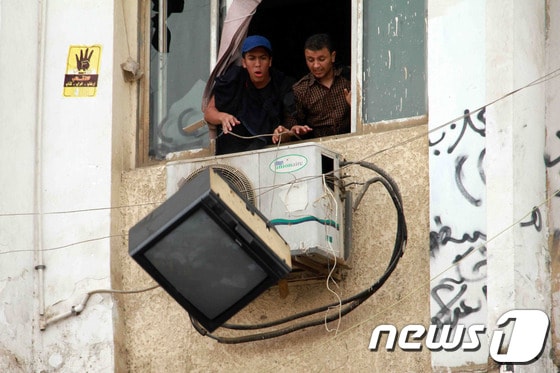 30일(현지시간) 이집트 카이로의 알 아즈하르 대학 학생들이 反군부 시위를 벌이면서 빌딩 창문에서 TV를 던지고 있다. 이집트 보안군은 축출된 모하메드 무르시 전  대통령 지지 시위를 벌이는 학생들을 해산시키기 위해 최루탄을 쐈다. © AFP=뉴스1  