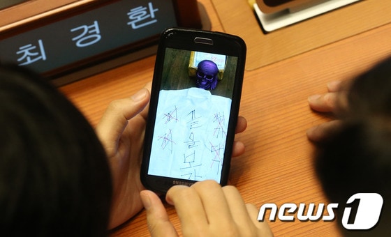 새누리당 하태경 의원이 최경환 원내대표에게 7일 서울 여의도 국회에서 열린 본회의에서 해골 모형과 '끝을보자'라고 적힌 사진을 보여주고 있다. 2013.10.7/뉴스1 © News1 송원영 기자