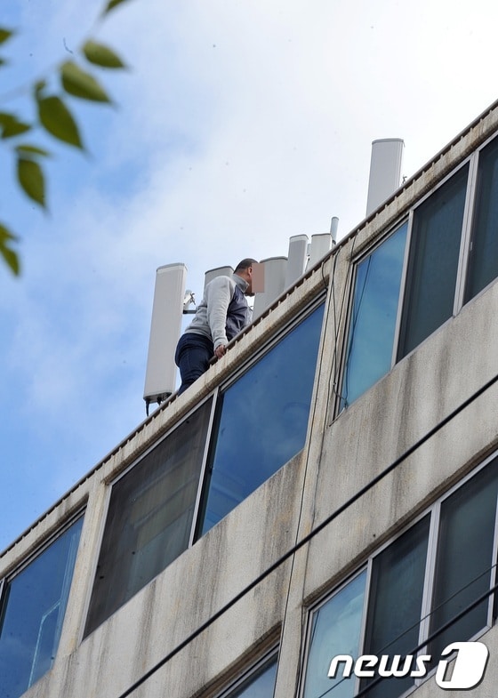 22일 낮 12시20분경 중국인 뤼모(43)씨가 제주시 연동 신광초등학교 인근 7층 짜리 아파트 건물 옥상 난간에 걸터 앉아 출동한 경찰, 119구조대와 대치중이다. 뤼씨는 제주시내 모 카지노에서 도박을 하다 8000만원을 잃자 불만을 품고 이같은 짓을 저지른 것으로 알려졌다. 2013.11.22/뉴스1 © News1 이상민 기자
