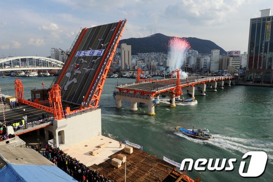 27일 오후 부산의 근대사를 상징하는 영도대교 상판이 47년 만에 다시 들어 올려지고 있다. 국내 유일의 도개 기능 교량인 영도대교는 개통식 이후 매일 낮 12시부터 15분간 상판을 들어올린다. 롯데쇼핑과 롯데호텔은 이번 영도대교 공사비 1100억원을 기부채납 방식으로 전액 부담했다. 2013.11.27/뉴스1 © News1 전혜원 기자