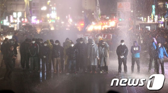 한국진보연대, 민주노총을 비롯한 100여개 노동조합과 시민사회단체 참가자들이 7일 오후 서울역광장에서 '박근혜 정부 규탄 비상시국대회'를 마치고 도심으로 행진을 벌이다 종로3가에서 인도로 물러날 것을 요구하는 경찰이 쏜 물대포를 맞고 있다. 2013.12.7/뉴스1 © News1   한재호 기자