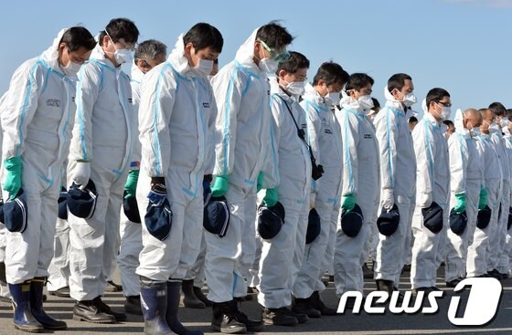 후쿠시마 원전 근처에서 방사능 차단복을 입고 수색작업을 벌이고 있는 경찰관들이 3.11 일본 대지진 2주년인 11일 강도9의 지진이 발생한 오후 2시46분 희생자들을 위해 묵도하고 있다. ©AFP=News1 