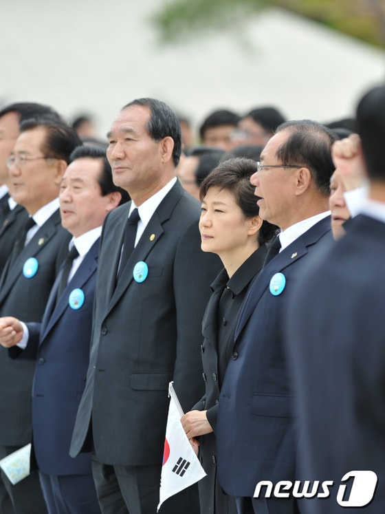 박근혜 대통령이 18일 오전 광주 북구 운정동 5·18국립묘지에서 열린 5·18 민주화운동 33주년 기념식에 참석했다. 보훈처는 &#39;임을 위한 행진곡&#39; 제창을 거부했지만, 대부분의 참석자들이 합창단의 합창이 시작되자 자발적으로 자리에서 일어나 &#39;임을 위한 행진곡&#39;을 제창했다. 박근혜 대통령은 이날 노래를 부르지는 않았지만 태극기를 들고 자리에서 일어났다. 2013.5.18/뉴스1 © News1 정회성 