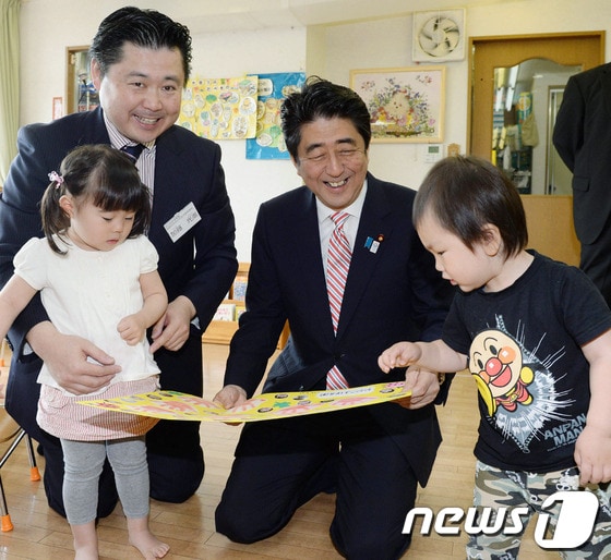  아베 신조 일본 총리(가운데)가 21일 일본 요코하마 소재의 유치원에서 아이들과 함께 놀고 있다. 요코하마시는 여성의  출산 후 복직 불가능 문제를 해결하기 위해 유치원과 보육원의 입학을 기다리는 대기인원을 줄이는 정책을 시행하고 있다.  © AFP=News1  