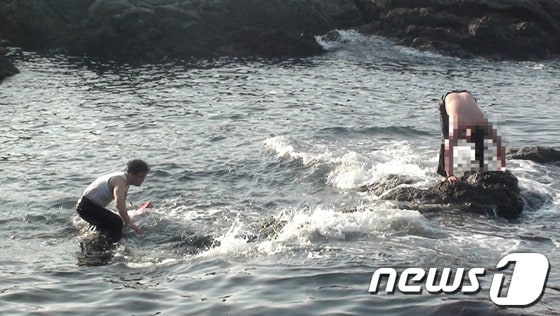 부산해경 구조요원이 만취 상태로 수영하다 해상에 고립된 김씨를 구조하고 있다.(부산해양경찰서 제공)© News1