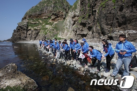 23일 독도를 방문한 대구은행 사이버독도지점 탐방단이 고유종인 어린 왕전복을 방류하고 있다./사진제공=대구은행© News1