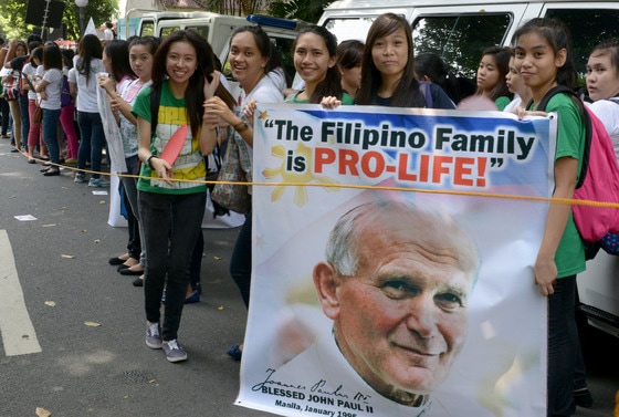 요한 바오로 2세 전 교황 사진을 든 필리핀 가톨릭 신자들이 9일(현지시간) 대법원 앞에서 정부가 피임법과 성 교육을 지원토록 규정한 법률에 반대하고 있다. 필리핀은 전체 인구의 80%가 가톨릭 신자로 가톨릭 교계는 최근 통과된 이 법안에 대해 강력히 반대하고 있다. 현재 대법원에서 법안을 심사하고 있다. © AFP=뉴스1  