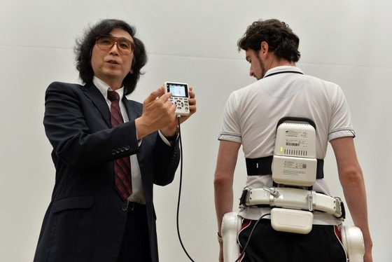 일본 로봇 기업 사이버다인(Cyberdyne) 의 회장 산카이 요시유키 쓰쿠바 대학 교수(왼쪽)가 5일 쓰쿠바 본사에서 새로 개발한 의학용 신체보조 로봇 슈트인 HAL을 선보이고 있다. 사람의 동선을 파악하여 움직이는 것을 도와주는 HAL은 장애인과 노인 등의 재활치료에 도움되며 유럽 인증국에서는 의학용 장치로 이미 허가를 받은 상태다. © AFP=뉴스1  