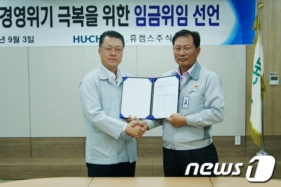 여수국가산단 내 휴켐스 최규성 대표이사(왼쪽) 와 김재학 노조위원장(오른쪽)이 임금협상 위임장에 서명한 후 악수를 하고 있다.© News1 김상렬 기자