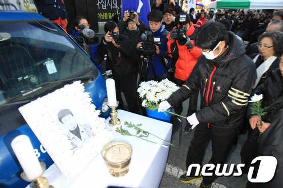 '박근혜 사퇴, 특검 실시'를 외치며 서울역 앞 고가도로에서 분신해 숨진 고 이남종(40)씨의 영결식이 4일 오후 광주 금남로에서 진행됐다. 이씨의 동생이 헌화하고 있다. 2014.1.4/뉴스1 © News1 김태성 기자