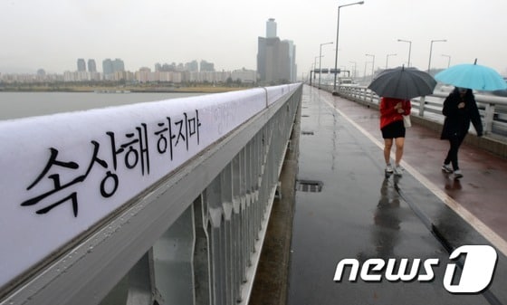 21일 오후 서울 마포대교에 적힌 자살예방 문구 옆으로 시민들이 지나가고 있다. 최근 4년간 전국 교량(다리)에서의 자살이 2.3배로 증가한 것으로 나타났다. 특히 마포대교에서 가장 자살 시도가 많은 것으로 조사됐다. 2014.10.21/뉴스1 ⓒ News1 손형주 기자