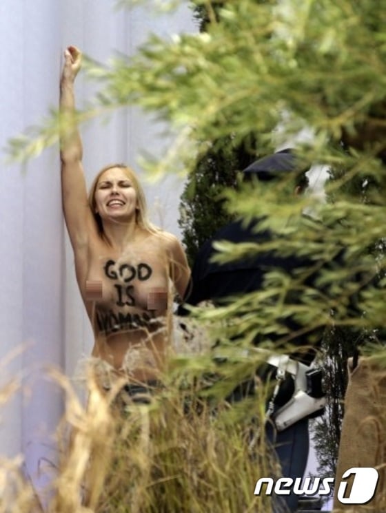 성탄절인 25일 바티칸 베드로광장서 토플리스 시위하는 페멘 여성운동가. 그의 가슴에는 '신은 여성이다'라는 문귀가 쓰여있다. ⓒ AFP=News1