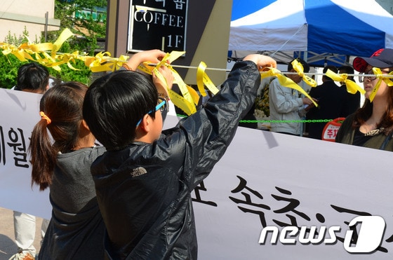 1일 세월호 참사 희생자들을 추모하기 위해 속초시내 S호텔 앞에 마련된 속초고성양양 합동 분향소에 어린이 2명이 정성스레 노란리본을 메달고 있다. 2014.5.1/뉴스1 © News1   엄용주 