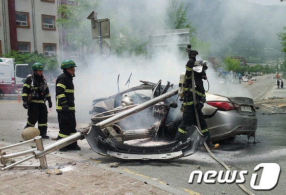 25일 낮 12시 22분께 강원 정선군 정선읍 북실리 현대아파트 앞 회전교차로 인근 가로수를 들이 받은 소나타 승용차&#40;운전자 전모씨·52&#41;에 불이 나 소방대원들이 진화 및 구조작업을 벌이고 있다. 이 사고로 2명의 사상자가 발생했다.&#40;정선소방서 제공&#41; 2014.5.25/뉴스1 © News1   이예지 기자