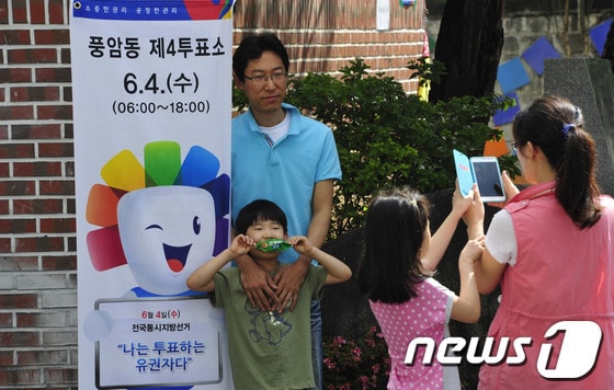 6·4지방선거일인 4일 광주 서구 풍암동 4투표소에는 투표를 마친 한가족이 투표소 앞에서 인증샷을 찍고 있다.2014.6.4/뉴스1 © News1   김태성 기자