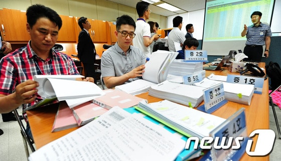 노인을 대상으로 고수익 보장 명목으로 210억원대 금융 사기 조직을 운영한 피의자 검거 브리핑이 열린 15일 오전 전북지방경찰청 기자실에서 관련 경찰관들이 브리핑에 앞서 압수 자료를 정리하고 있다. 2014.7.15/뉴스1 © News1 김대웅 기자