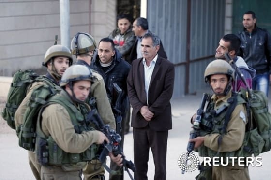 Palestinian man argues with an Israeli soldier during a search for a missing Israeli near the West Bank city of Hebron
