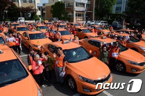 해치택시 운전사들로 구성된 구로구 나들이 봉사단이 5월 13일 오전 서울 구로구청 마당에서 지역 저소득층 노인, 장애인과 함께 인천 강화도로 나들이 봉사활동을 떠나기 앞서 배웅객들에게 손을 흔들고 있다. 2015.5.13 ⓒ News1 정회성 기자