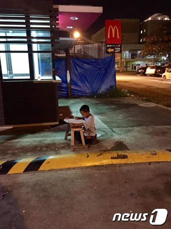 홈리스 필리핀 소년 다니엘 카브레라가 한밤중 맥도날드 매장 불빛에 의존해 공부하고 있다. ⓒ AFP=뉴스1