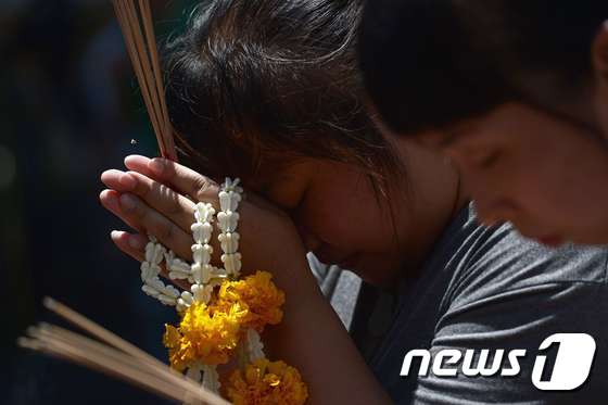 19일(현지시간) 다시 문을 연 태국 방콕 에라완 사원을 찾은 여성들이 테러 희생자들을 위해 기도하고 있다. ⓒ AFP=뉴스1