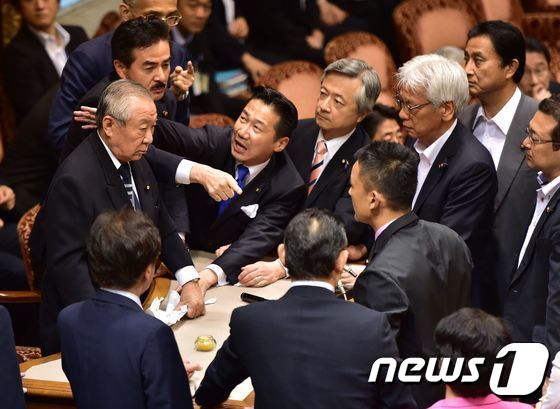 고노이케 요시타다(鴻池祥肇) 참의원 평화안전법제 특별위원회 위원장(자민, 좌측)이 17일 오전 안보법안을 비판하는 야당 의원들에 둘러싸여 있다. ⓒ AFP=News1