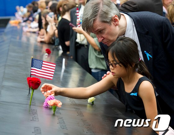 한 소녀가 미국 뉴욕 맨해튼에 있는 9·11 기념박물관의 추모비를 들여다보고 있다. 9.11기념박물관은 테러로 폭파된 세계무역센터 쌍둥이 빌딩이 있던 그 자리에 설립됐다. ⓒ AFP=뉴스1