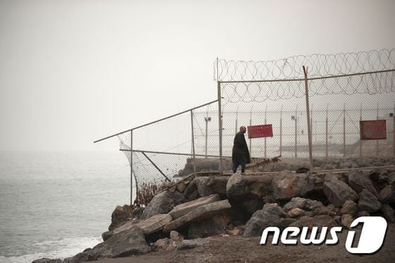한 남성이 모로코와 스페인령 세우타 국경에 설치된 철조망 옆을 지나치고 있다. ⓒ AFP=뉴스1