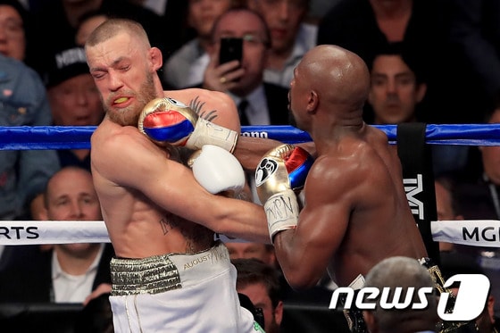 코너 맥그리거(왼쪽)가 27일 열린 플로이드 메이웨더와의 경기에서 펀치를 허용하고 있다. ⓒ AFP=News1