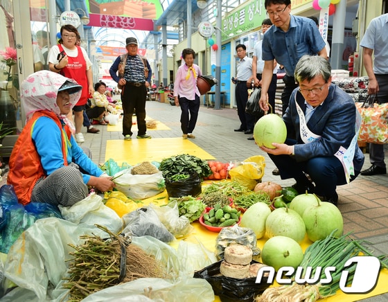 19일 경북 고령군 고령대가야시장에서 열린 추석대목 전통시장 장보기 행사에 참여한 곽용환 고령군수가 할머니가 팔려고 가져온 박을 살펴보고 있다.(고령군제공)2017.9.19/뉴스1 ⓒ News1 정우용 기자