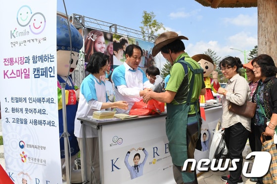 평창효석문화제가 열리고 있는 7일 강원 평창군 봉평면 봉평전통시장에서 한국관광공사, 평창군, 봉평전통시장상인회가 함께하는 K스마일 친절캠페인이 열린 가운데 심재국 평창군수(가운데)와 강옥희 관광공사 국제관광진흥본부장(왼쪽)이 상인들을 대상으로 진철 봉지를 나눠주고 있다.(평창군 제공).2017.9.7/뉴스1 ⓒ News1 권혜민 기자