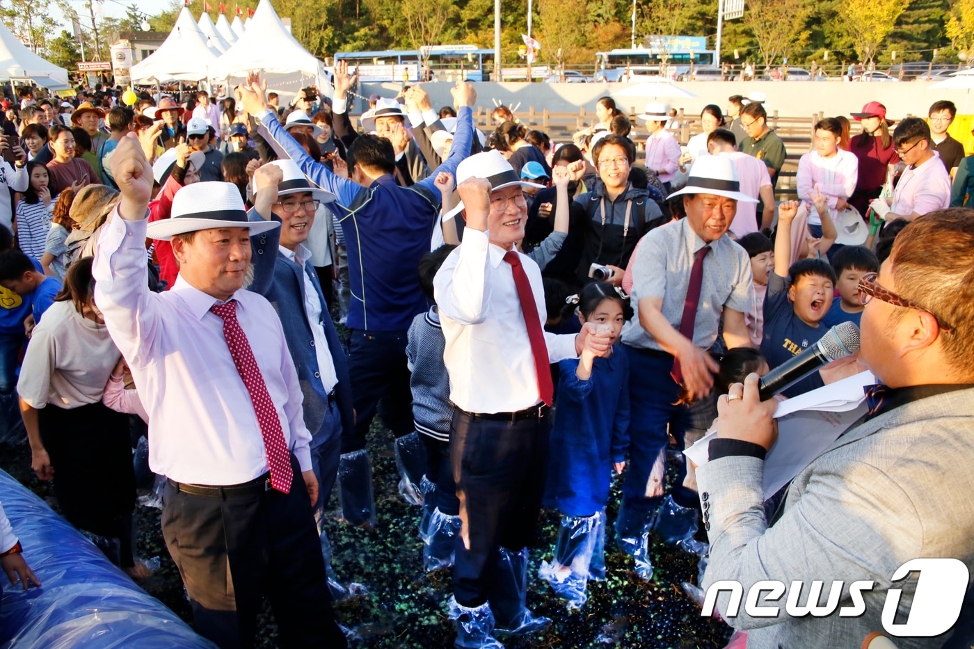 지난해 10월7일 경북 영천한의마을에서 열린 와인페스타에서 와인어불러담기 행사에 참여한 박종운 영천시의장(왼쪽)이 최기문 시장(가운데), 어린이들과 함께 와인을 으깨고 있다. 이날 으깬 와인은 1년동안 숙성을 거쳐 행사 참가자집으로 배달된다 2018.10.7/뉴스1 ⓒ News1 정우용 기자