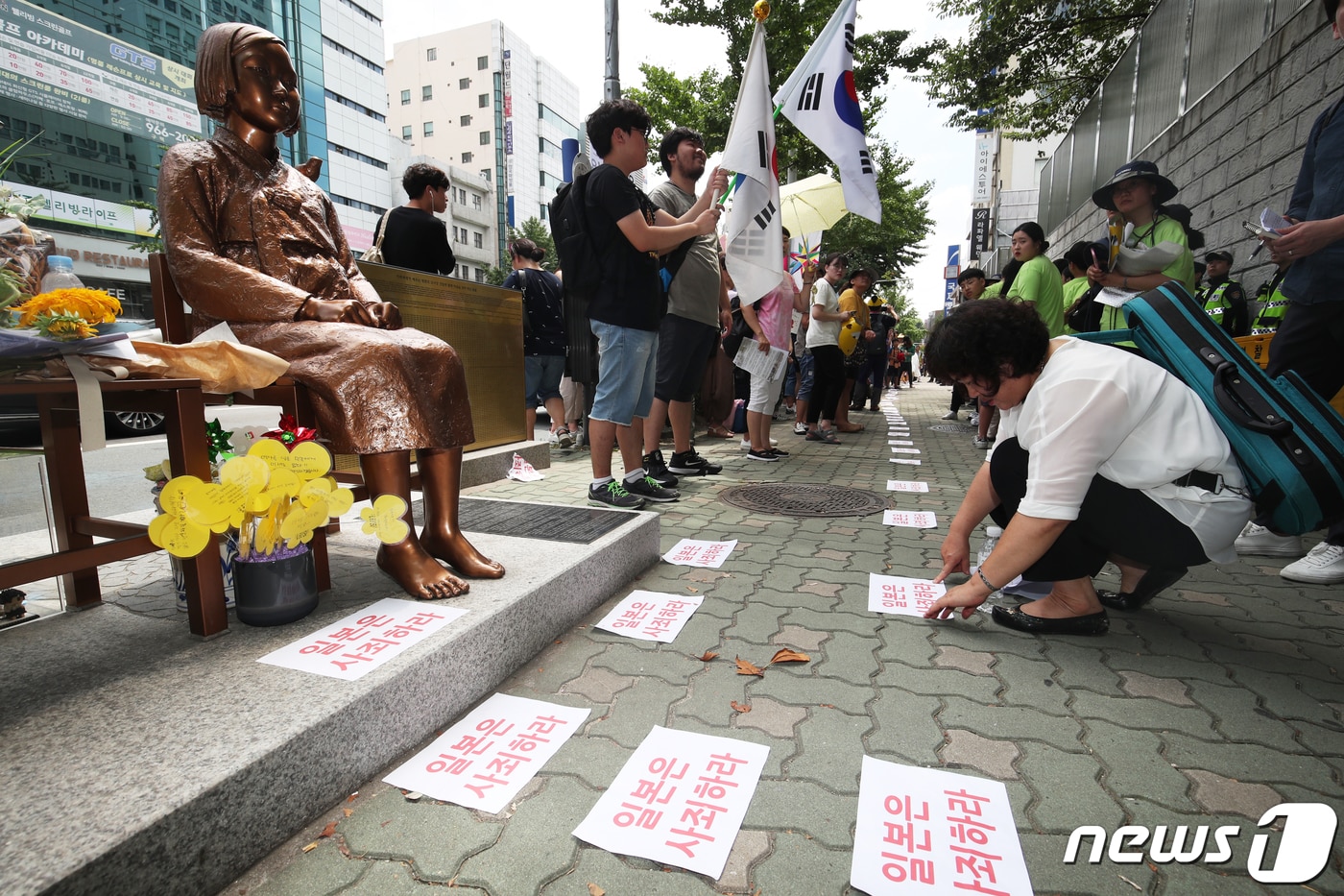 부산 동구 일본영사관 앞 소녀상 인근에서 열린 '세계 일본군 위안부 기림일 기념 부산 44차 수요시위'에 참가한 참석자들이 '일본은 사죄하라'는 문구가 담긴 종이를 소녀상 앞에 이어 붙이고 있다. 2019.8.14/뉴스1 ⓒ News1 DB