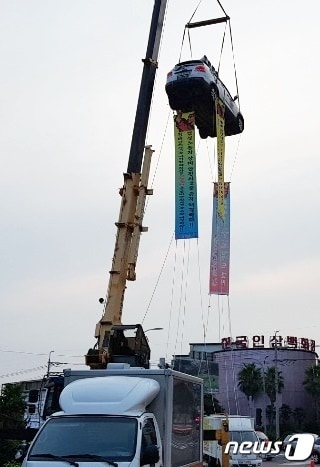 19일 오전 6시쯤 제주시 연동 신광사거리에서 건설노동자가 장비 안전사고 해결을 촉구하며 크레인에 승용차를 매달아 농성 중이다. 승용차 안에는 현재 노동자 1명이 탑승하고 있는 것으로 알려졌다&#40;제주소방안전본부 제공&#41;2019.8.19/뉴스1 ⓒ News1 고동명 기자