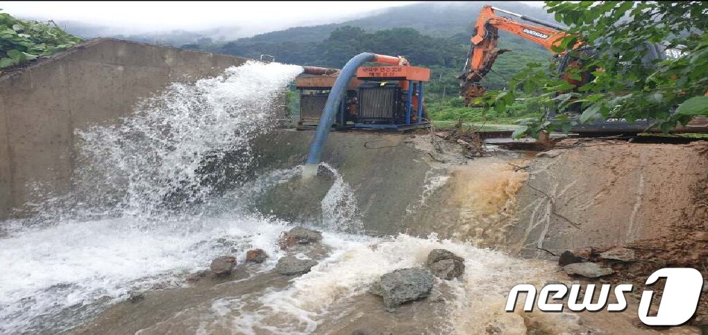 29일 내린 집중호우로 경북 청도군 내리리 대능저수지 만수위가 가까워지자 청도군이 선제적 피해 예방을 위해 물넘이를 깨 수위를 조절하고 양수기를 동원해 물을 퍼내고 있다. 7월 한달간 청도군에는 487mm의 비가 내렸다 (청도군 제공)2020.7.29/뉴스1 ⓒ News1 정우용 기자