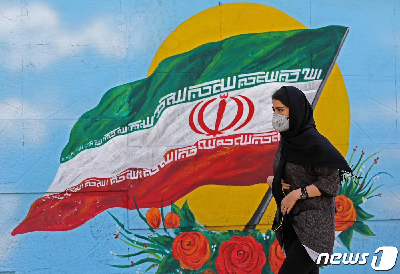 이란 국기 그림 앞을 한 여성이 지나가고 있다. ⓒ AFP=뉴스1