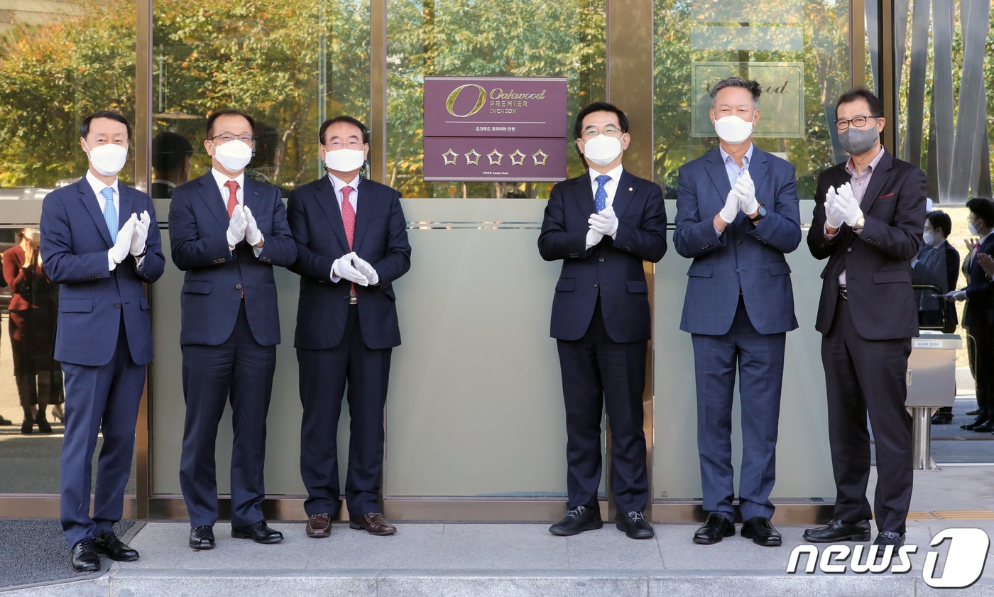 한무컨벤션(주)에서 운영하는 오크우드 프리미어 인천이 한국관광협회중앙회가 시행하는 호텔 등급심사에서 가족호텔로서 최초로 최고 등급인 5성 등급을 획득했다. 22일 심영철 오크우드 프리미어 인천 총지배인, 주시보 ㈜포스코인터내셔널 사장, 조윤영 한무컨밴션㈜ 사장, 더불어민주당 정일영 국회의원, 민민홍 인천관광공사 사장 ,이임혁 인천시관광협회 회장(사진 왼쪽부터)이 오크우드 프리미어 호텔 앞에서 현판식을 하고 있다. 2021.10.22/뉴스1 ⓒ News1 정진욱 기자