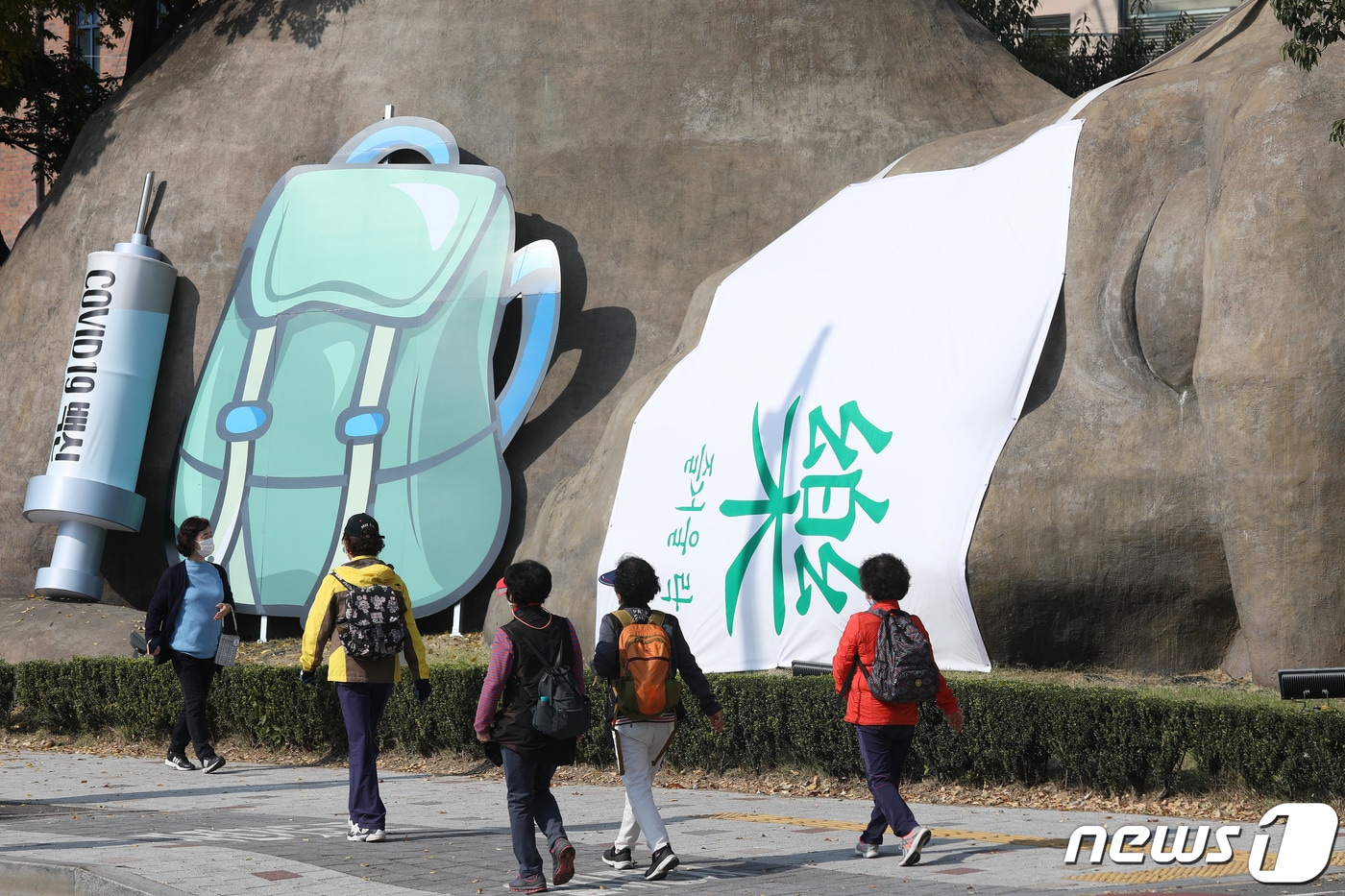 2021년 대구 달서구 선사유적공원 진입로에 설치된 거대 원시인 조형물 마스크에 단계적 일상회복을 기원하는 '즐거울 락(樂)' 글자를 비롯해 코로나19 백신접종 주사기와 여행용 배낭이 설치돼 눈길을 끌고 있다. 2021.11.2/뉴스1 ⓒ News1 공정식 기자