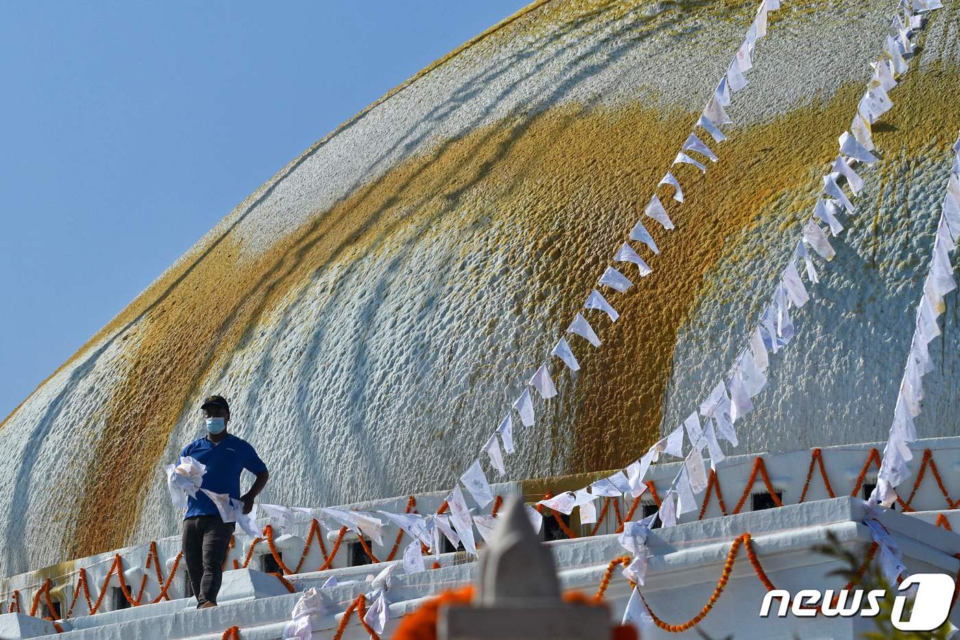 한 불교 신자가 18일(현지시간) 네팔 카트만두 부다나트 불탑에 기도가 적힌 깃발을 걸고 있다. 2021.12.19/news1 ⓒ AFP=뉴스1 ⓒ News1 김민수 기자