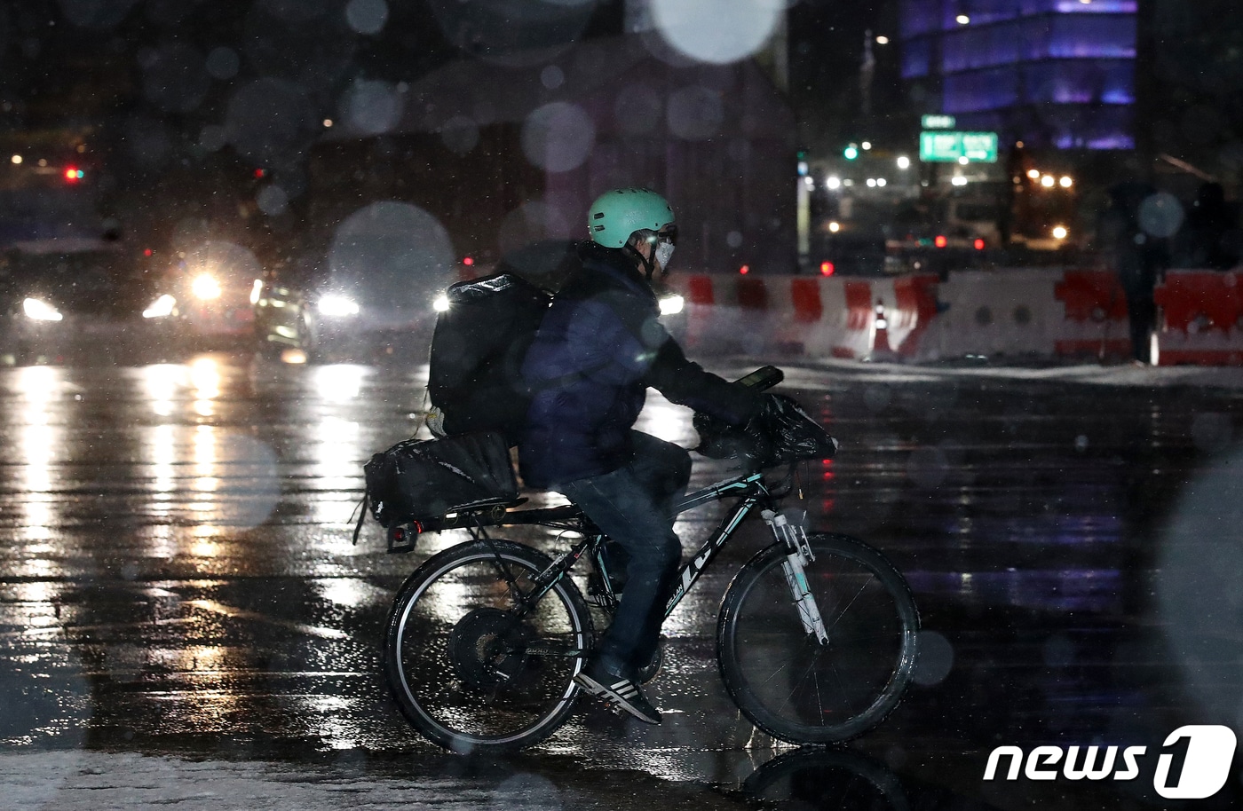 서울 전역과 경기북부 지역에 대설주의보가 내려진 3일 오후 서울 종로구 광화문역 인근 세종로에서 한 배달원이 자전거를 타고 횡단보도를 건너고 있다. 2021.2.3/뉴스1 ⓒ News1 김진환 기자