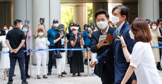 조국 전 법무부 장관이 25일 서울 서초구 중앙지방법원에서 열린 공판에 출석하자 지지자들이 조 전 장관이 쓴 회고록 '조국의 시간'을 든채 응원하고 있다. 조 전 장관은 딸 조민씨의 부산대 의학전문대학원 장학금 부정수수 관련 뇌물수수 및 청탁금지법 위반, 사모펀드 의혹 관련 공직자윤리법 위반 등 11개 혐의로 아내 정경심 동양대 교수와 함께 기소됐다. 이날 공판에는 조민씨가 증인으로 출석한다. 2021.6.25/뉴스1 ⓒ News1 안은나 기자