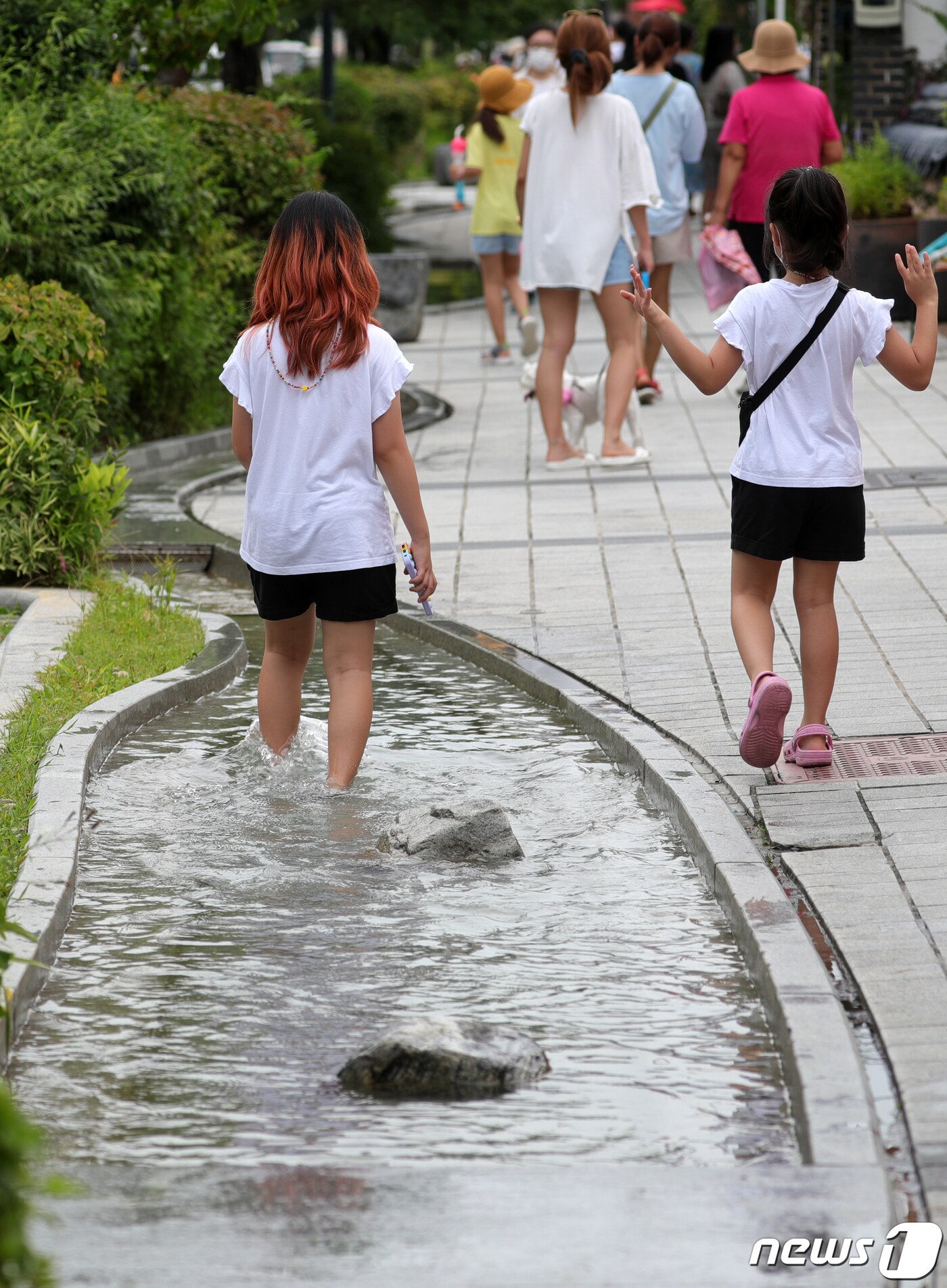 휴가철을 맞아 전북지역 대표관광지인 전주 한옥마을에 관광객들의 발길이 이어지고 있는 3일 전주 한옥마을에서 한 어린이가 인공 실개천에 발을 담근 채 걷고 있다. 2021.8.3/뉴스1 ⓒ News1 유경석 기자