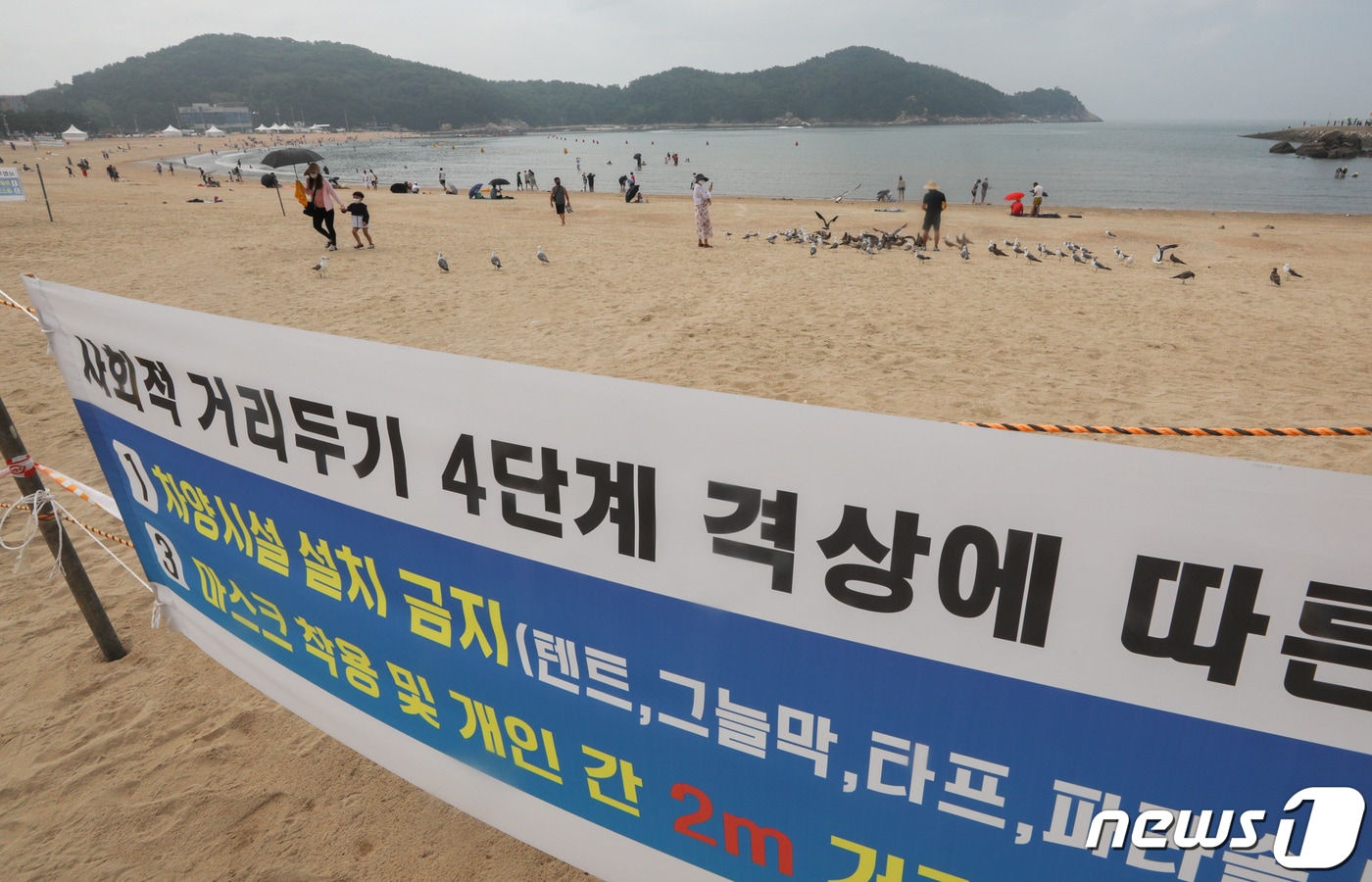 본격적인 휴가철을 맞은 지난 3일 오전 인천광역시 중구 을왕리해수욕장에서 거리두기 방역수칙 안내 플래카드 뒤로 피서객들이 물놀이를 즐기거나 모래사장에서 휴식을 취하고 있다. 2021.8.3 /뉴스1 ⓒ News1 성동훈 기자