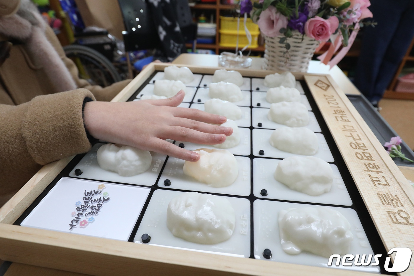 11일 오전 대구 남구 대명동 시각장애인 교육기관 대구광명학교에서 열린 2021학년 졸업식에서 초등학교 과정 졸업생이 3D프린터로 제작된 졸업앨범에 손을 올려 친구와 선생님 얼굴을 만져보고 있다. 대구광명학교는 크리에이티브팩토리의 도움을 받아 졸업생에게 친구와 선생님의 얼굴과 음성파일이 담긴 특별한 졸업앨범을 선물했다. 2022.1.11/뉴스1 ⓒ News1 공정식 기자