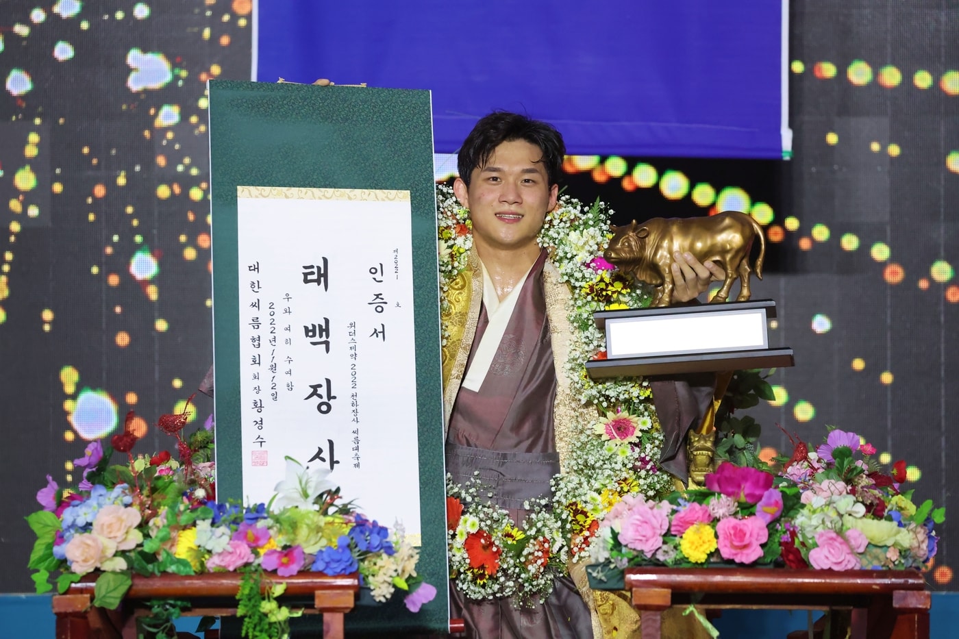 12일(토) 울산광역시 울주군 작천정운동장 씨름특설경기장에서 열린 ‘위더스제약 2022 천하장사씨름대축제’ 태백장사(80kg이하)에 등극한 노범수(울주군청)가 장사꽃가마를 타고 장사인증서와 황소트로피를 들고 기념사진을 찍고 있다.(대한씨름협회 제공)