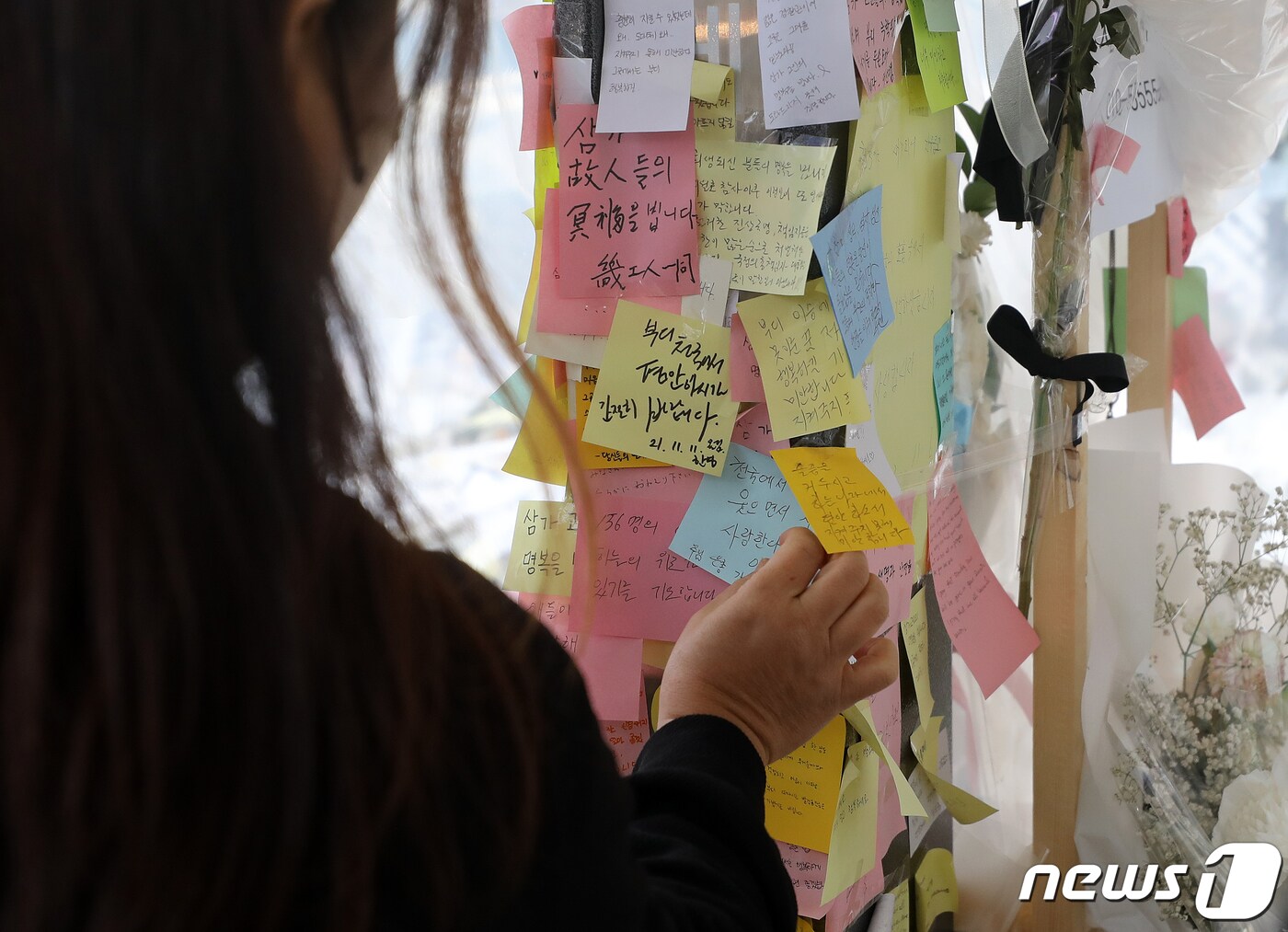 13일 오전 서울 용산구 이태원역 1번 출구에 마련된 이태원 참사 희생자 추모공간에서 한 시민이 추모하는 문구를 붙이고 있다. 2022.11.11/뉴스1 ⓒ News1 김진환 기자