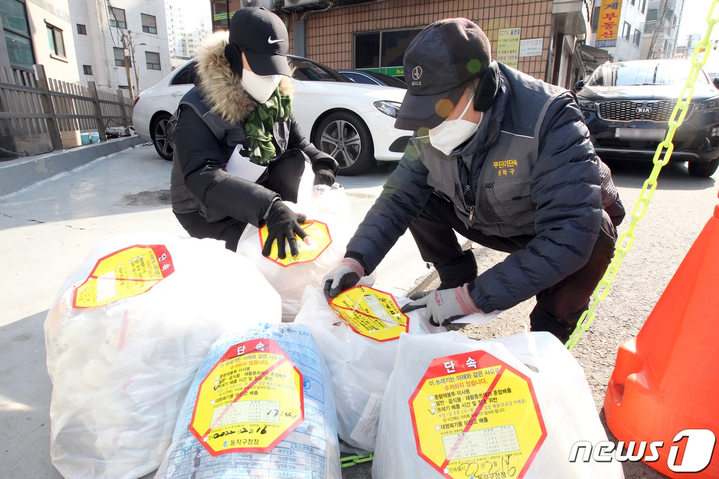 서울 동작구청 쓰레기 무단투기 단속반 직원들이 16일 오후 관내 주택가 밀집지역에서 쓰레기 배출시간 및 장소위반으로 적발된 종량제 봉투에 스티커를 부착하고 있다. (동작구청 제공) 2022.2.16/뉴스1